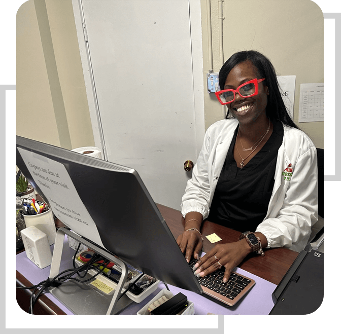 A woman sitting at her computer desk wearing red glasses.