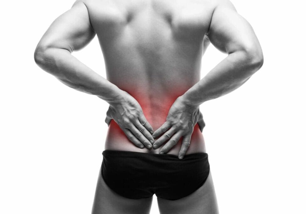 A man with his hands on the back of his lower body.